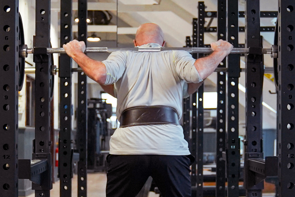 Client performing a squat whilst wearing a weightlifting belt